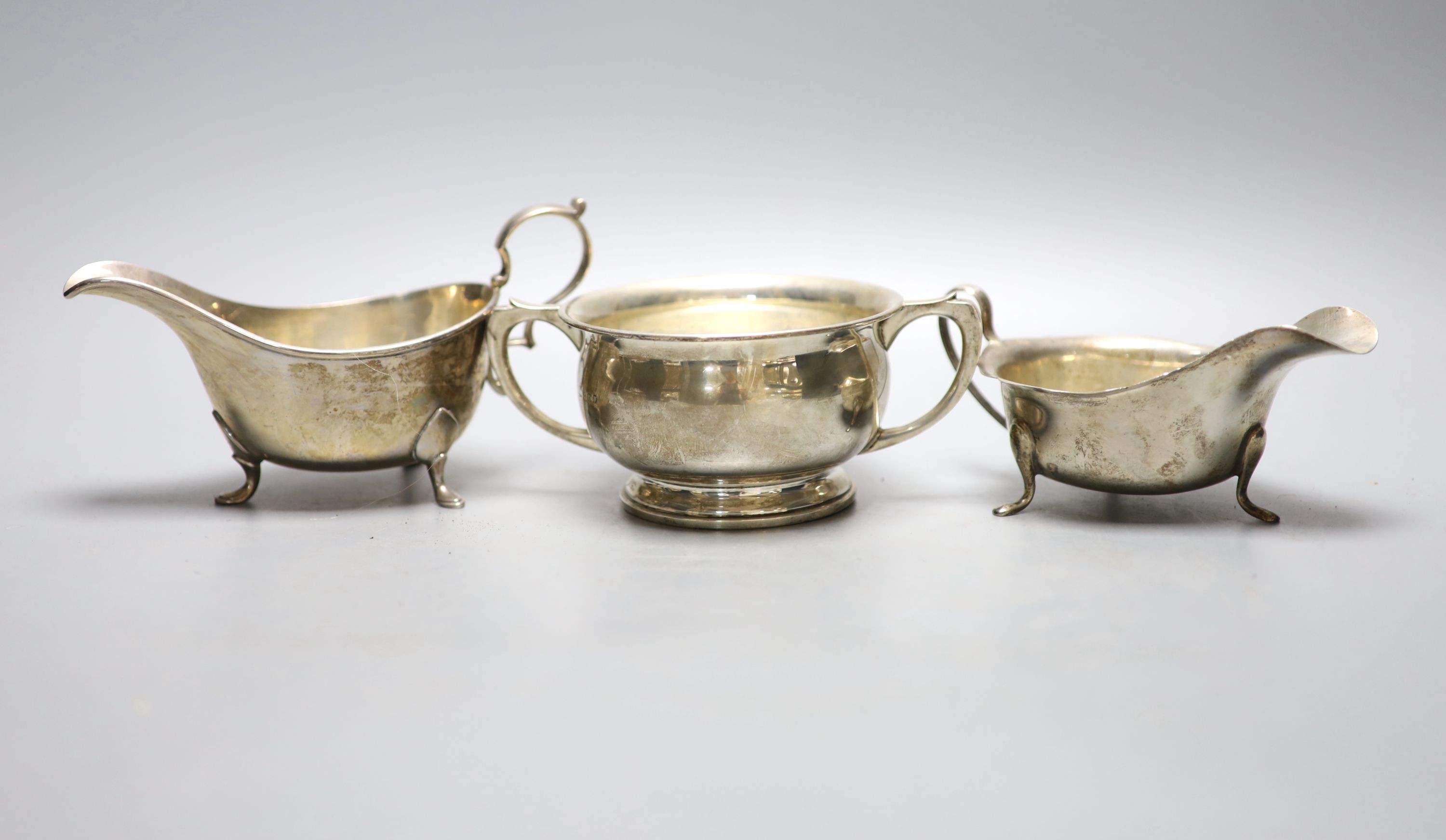 Two George V silver sauceboats and a similar silver two handled sugar bowl, with engraved inscription, 15.5oz.